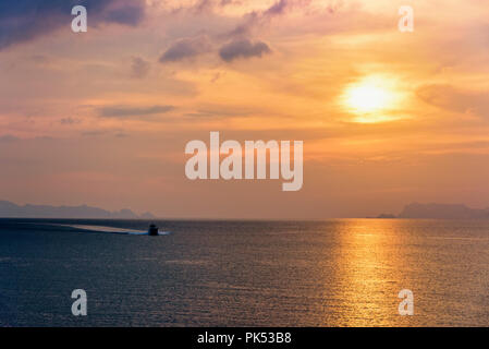 Il motoscafo per la pesca sul mare di ritornare a Riva durante il tramonto in mezzo alla natura e il bellissimo cielo. Foto Stock