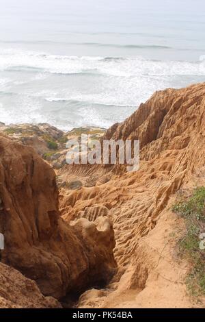 Oceanside profonde scogliere arancione in primo piano lungo la spiaggia a Torrey Pines State preservare, San Diego, CA Foto Stock