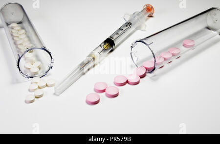 Le pillole di prescrizione e ago medicale. Siringa e la Prescrizione di pillole isolato su uno sfondo bianco. Bianco e rosa pillole. Foto Stock