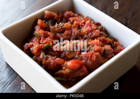 Meze turchi Acili Ezme o acuka fatta con pomodori freschi e spezie in ceramica quadrata ciotola. Tradizionale cibo organico. Foto Stock