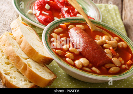 Fatti in casa a base di zuppa di fagioli con salsiccia è servita con pane e peperone vicino sul tavolo orizzontale. Foto Stock