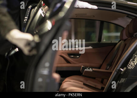 Chauffeur apertura porta auto per il trasporto di passeggeri Foto Stock