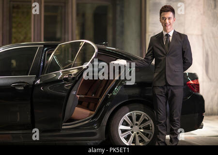 Chauffeur apertura porta auto per il trasporto di passeggeri Foto Stock