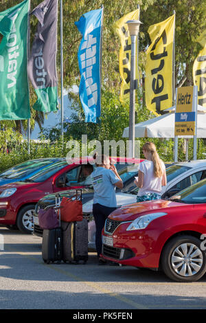 Giovane donna di noleggiare un auto e averlo ispezionato da attendant assistente presso l'Autonoleggio garage o deposito lotto. Foto Stock