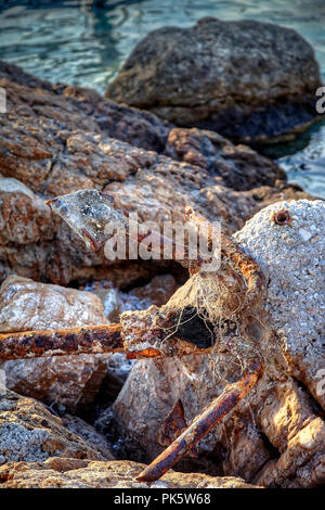 Vecchio arrugginito abbandonato di ancoraggio sulle rocce. Isolato. Immagine di stock. Foto Stock