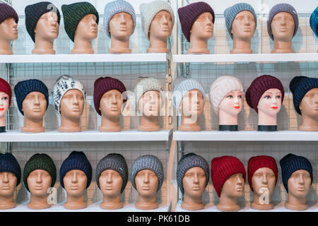 Cappelli di lana sulle teste argenteo dei manichini del negozio. una varietà di inverno femmina cappelli a maglia sul manichino teste. Foto Stock