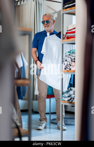 Elegante dai capelli grigi uomo nel negozio di abbigliamento Foto Stock