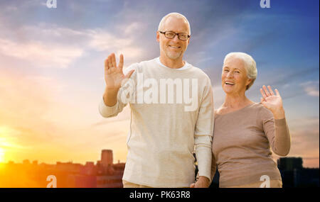 Felice coppia senior sventolare le mani sulla città tramonto Foto Stock