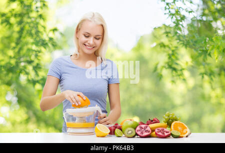 Felice donna fare succo di frutta o di arancia fresche Foto Stock