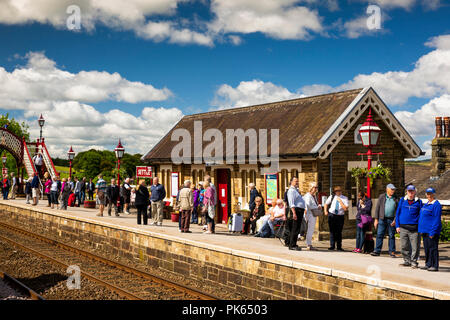 Regno Unito, Yorkshire, Settle,i passeggeri sulla stazione ferroviaria in attesa della piattaforma per stabilirsi a Carlisle Linea ferroviaria treno nella luce del sole Foto Stock