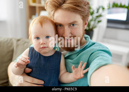 Padre felice con il bambino tenuto selfie a casa Foto Stock