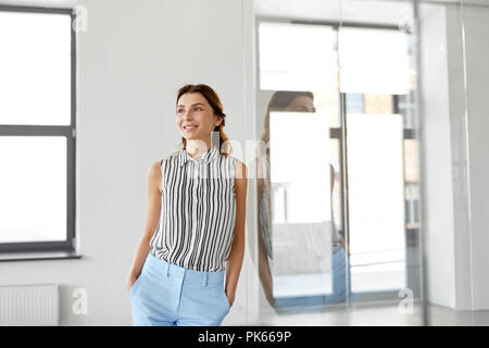 Imprenditrice sorridente in ufficio parete in vetro Foto Stock