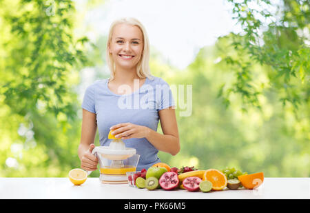 Donna felice la spremitura di succhi di frutta o di limone fresco Foto Stock