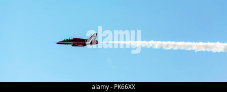 Un singolo RAF frecce rosse Hawk tagli a getto attraverso un cielo blu chiaro con il suo fumo bianco trail Foto Stock