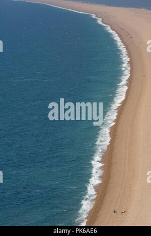 Guardando ad ovest lungo Chesil Beach dall'isola di Portland in una giornata di sole con un vento onshore che ha creato alcuni surf. Alcuni pescatori può essere visto fis Foto Stock