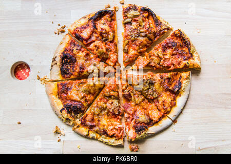 Una deliziosa pizza tonda tagliato in 8 fette sul pannello di legno Foto Stock