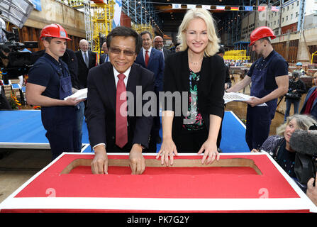 11 settembre 2018, Meclemburgo-Pomerania occidentale, Rostock: Tan Sri Lim Kok Thay, Presidente e CEO di Genting Hong Kong, e Manuela Schwesig (SPD), il primo ministro del Land Meclemburgo-Pomerania occidentale, messo monete in uno dei vettori sotto la prima sezione durante la festosa chiglia-cerimonia di posa per la prima classe globale nave da crociera presso il cantiere navale a Warnemünde. Il 'Global 1' sarà in grado di ospitare fino a 9.500 passeggeri, più di qualsiasi altra nave da crociera sul mercato internazionale. Il lussuoso rivestimento sarà 342 metri di lunghezza e 20 ponti di alta. Foto: Bernd Wüstneck/dpa Foto Stock