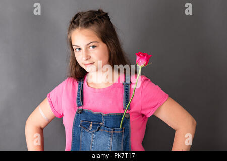 Felice giovani caucasici bellissima ragazza con rose fiore in tasca in posa e guardando alla fotocamera Foto Stock