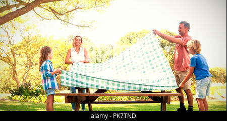 Famiglia di diffondere la tovaglia sul tavolo da picnic Foto Stock