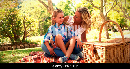 Figlia seduti sulle madri giro mentre avente picnic Foto Stock