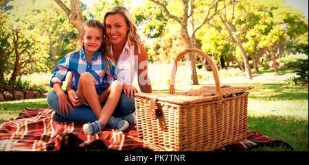 Figlia seduti sulle madri giro mentre avente picnic Foto Stock