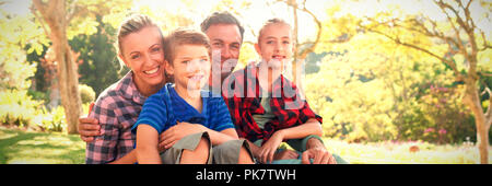 La famiglia felice seduta nel parco Foto Stock