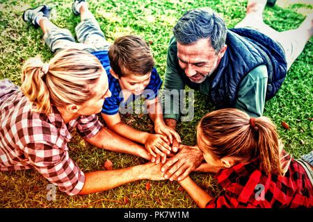 Famiglia giacenti e mettere le mani insieme in posizione di parcheggio Foto Stock