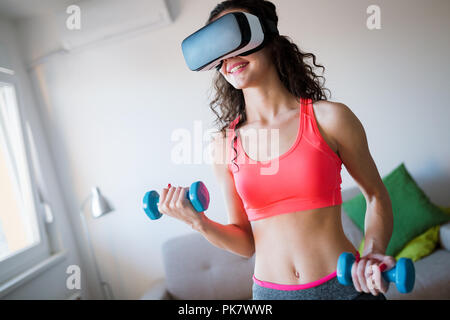 Giovane donna facendo esercizi indossando occhiali vr Foto Stock