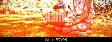 Nonna e nipote utilizzando laptop nel parco Foto Stock