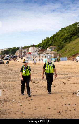 Regno Unito, Inghilterra, Yorkshire, Filey, spiaggia, PCSO e funzionario di polizia pattuglia su Filey sabbie al Coble sbarco Foto Stock