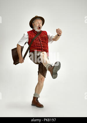 Ritratto di Oktoberfest senior uomo in hat, indossando tradizionali bavaresi vestiti andando a tutta lunghezza in studio. La celebrazione, oktoberfest, festival concept Foto Stock