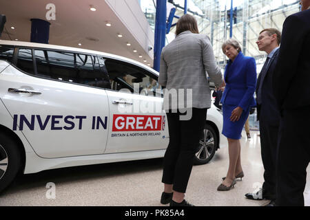 Il primo ministro Theresa Maggio guarda le automobili elettriche durante il veicolo a Emissioni Zero il vertice del CPI in Birmingham. Foto Stock