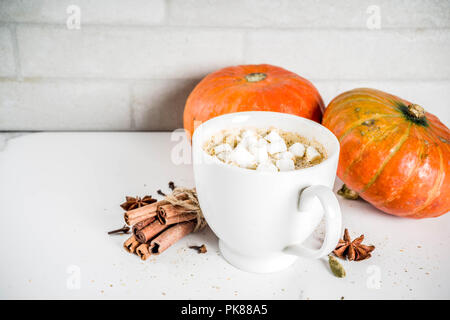 Zucca piccante caffè latte, autunno bevanda calda tazza di vetro, con zucche, cannella e spezie su marmo bianco di sfondo spazio di copia Foto Stock