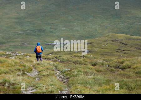 Uomo che cammina su una via al di sopra di un treno sul percorso da Fort William a telecomando Corrour Stazione ferroviaria sul Rannoch Moor nelle Highlands scozzesi, Foto Stock