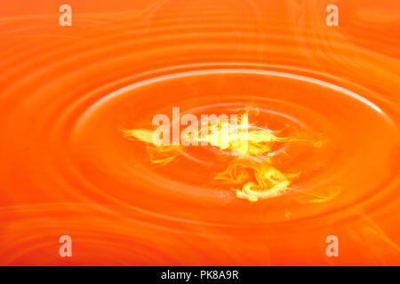 Giallo di goccioline di inchiostro di fare le onde in acqua rossa Foto Stock