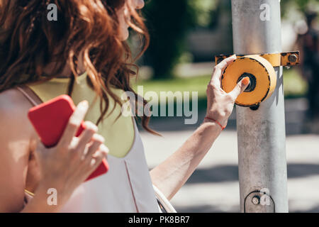 Ritagliato colpo di donna premendo il pulsante sul passaggio pedonale Foto Stock