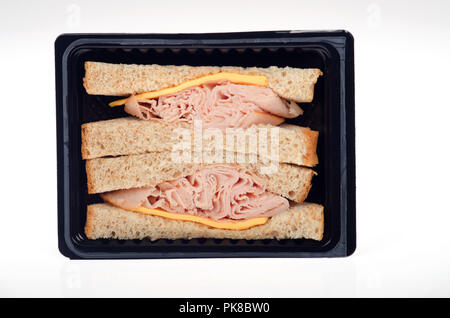 Preparato da asporto di tacchino affumicato e formaggio in sandwich di pane di grano in un pacchetto nero su sfondo bianco Foto Stock