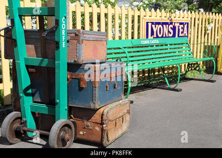 Corfe, Inghilterra - Giugno 03 2018: Vintage antique bagagli sul carrello accanto a un banco, sulla piattaforma a Corfe Castle stazione, sulla ferrovia a Swanage in Foto Stock