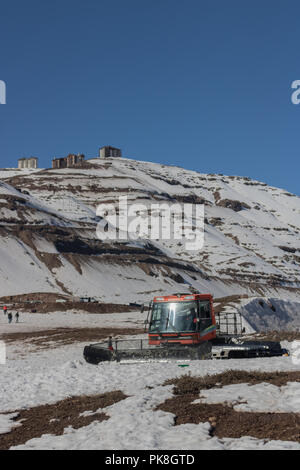 La Caterpillar Tractor per pulire il parcheggio di neve in montagna sul retro Valle Nevado Ski Resort, intorno ad alcune persone piace la montagna innevata Foto Stock