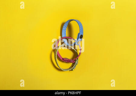 Set di tre cintura multicolore braccialetti mano giacenti su uno sfondo giallo. spazio libero per il testo pubblicitario Foto Stock