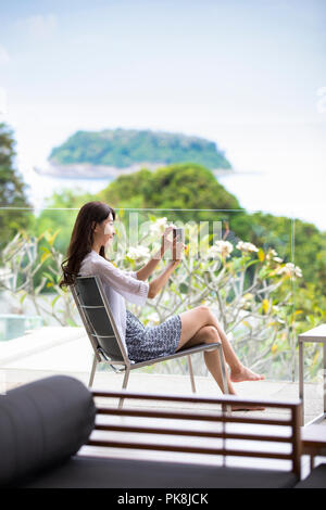 Felice giovane donna rilassante sul balcone Foto Stock