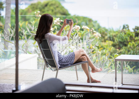 Felice giovane donna rilassante sul balcone Foto Stock