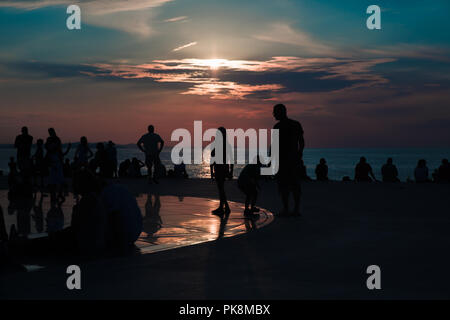 Un gruppo di persone in silhouette di guardare un bel tramonto dal Monumento al sole in Zadar, Croazia Foto Stock