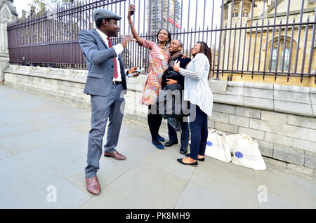 La famiglia in posa per un gruppo selfie davanti al Hosues del Parlamento, Westminster, Londra, Inghilterra, Regno Unito. Foto Stock