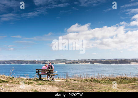 Vacanzieri seduti su una panchina su Towan testa affacciato sulla baia Newquay in Cornovaglia. Foto Stock