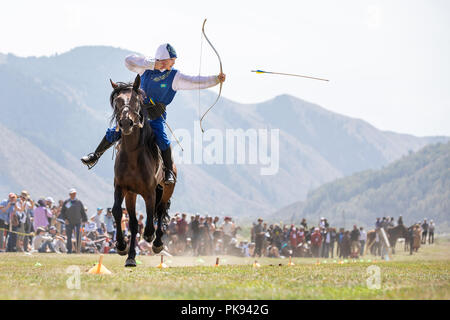 Città Cholpon-Ata, Kirghizistan - Settembre 6, 2018: Femmina archer mirando a un bersaglio durante un tradizionale cavallo tiro con l'arco della concorrenza. Foto Stock