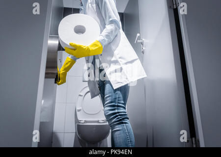 Bidello donna modifica carta nel wc pubblico Foto Stock