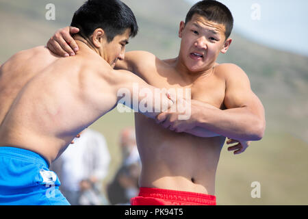 Il lago di Issyk-Kul, Kirghizistan - Settembre 6, 2018: Close-up di wo giovani uomini wrestling all'aperto durante il 2018 Mondo giochi nomade. Foto Stock