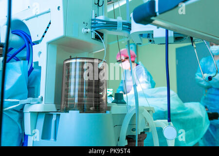 Frammento di apparecchi respiratori in sala operatoria, sfocare lo sfondo con il team medico chirurgo a lavorare in ospedale durante il loro lavoro. Foto Stock