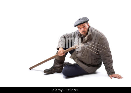 Uomo contadino con forcone su sfondo bianco, grave aspetto concentrato. Idea - la dura vita dei contadini Foto Stock